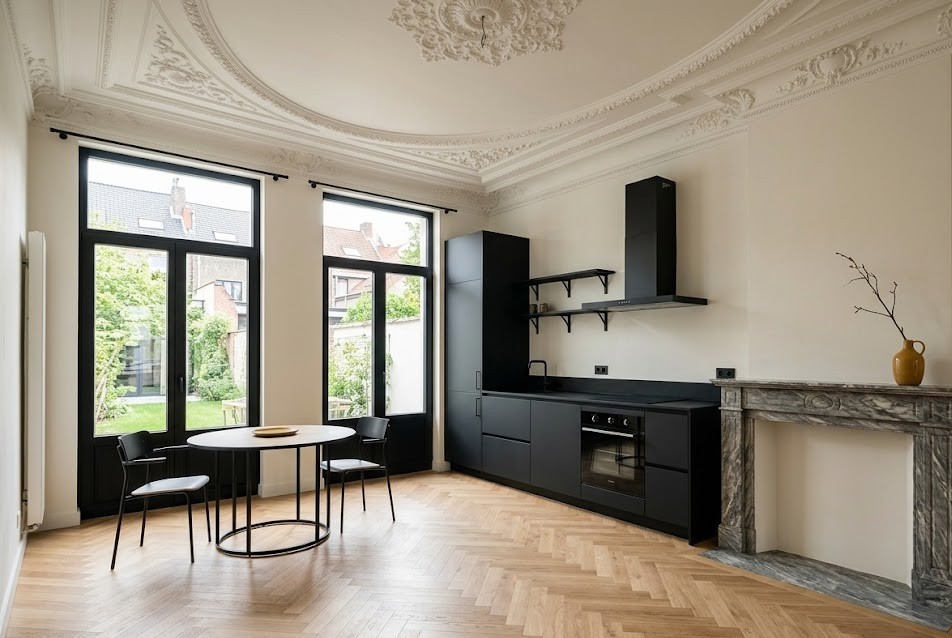 Gerenoveerd herenhuis met zwarte keuken en historisch stucplafond, resultaat van een professioneel herontwikkelingsproject