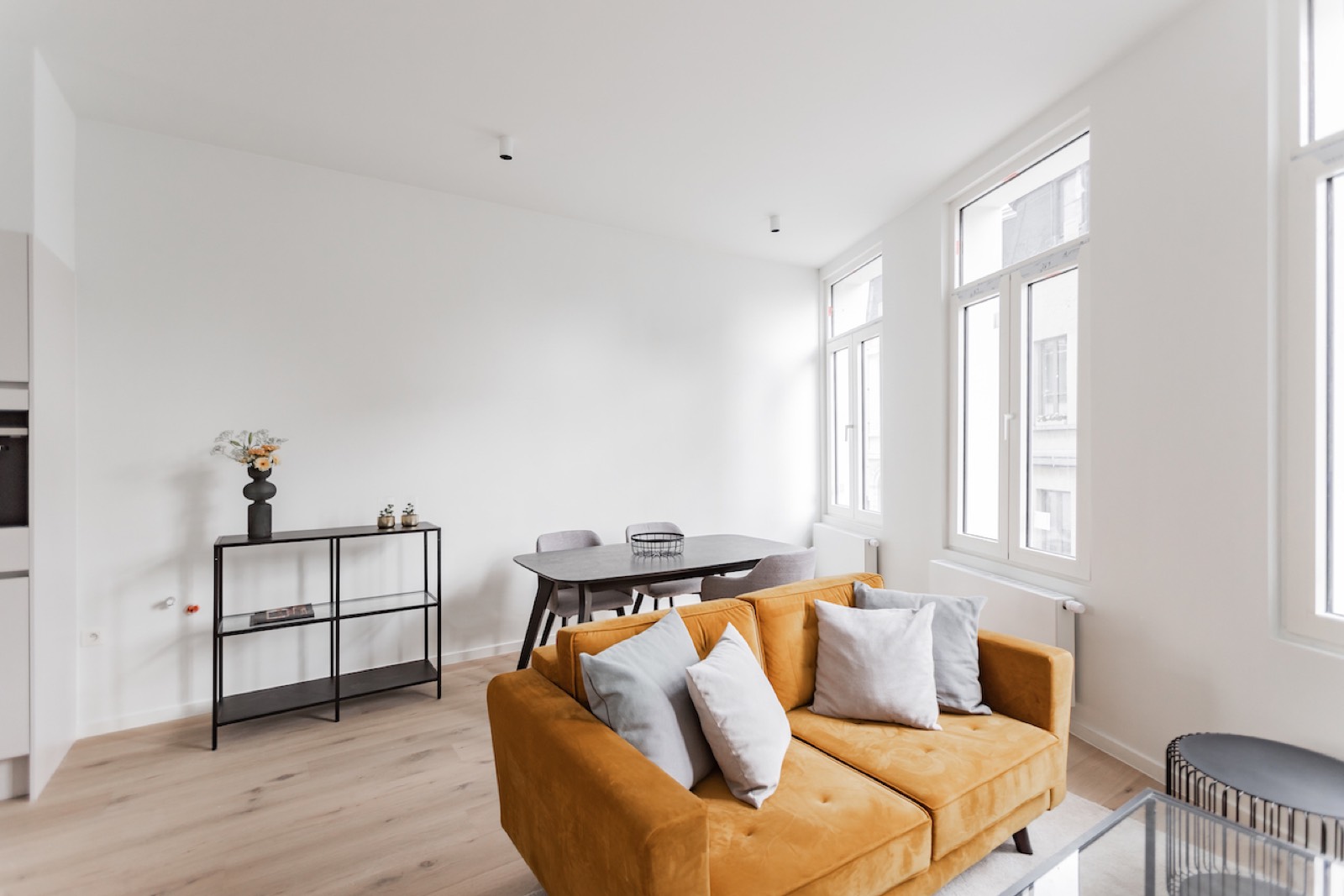 Lichte woonkamer met gele sofa en hoge ramen in een gesplitst Antwerps stadspand, illustratief bij renovatiefinanciering