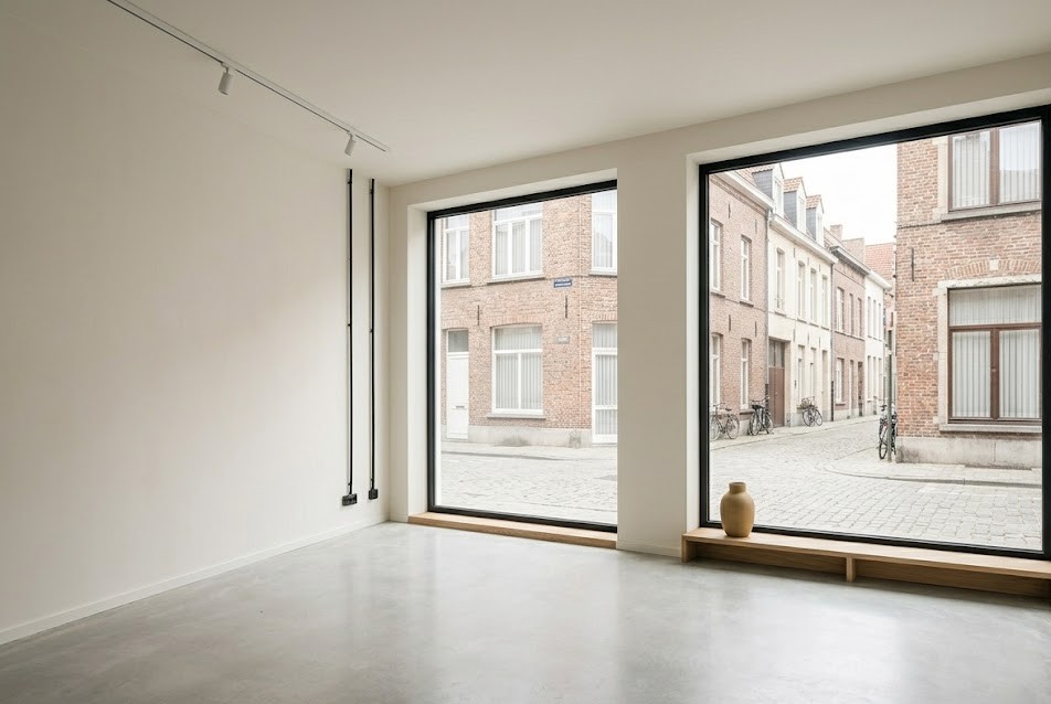 Lege commerciële benedenruimte met grote etalageramen en zicht op een Antwerpse straat, illustratief bij sale-and-leaseback van een bedrijfspand